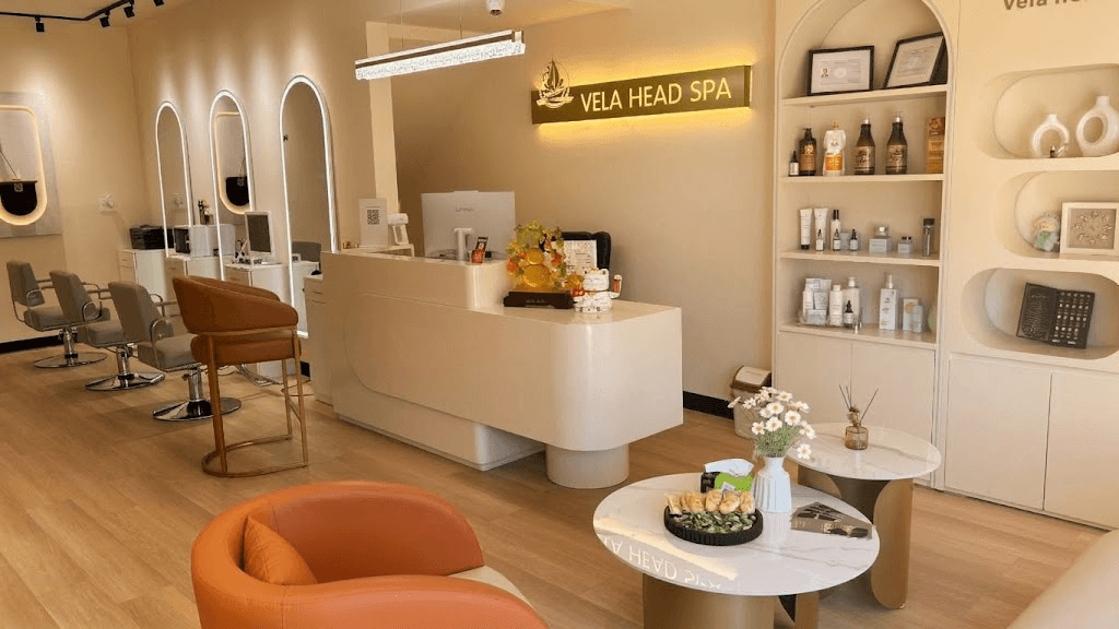 Vela Head Spa reception with the white front desk, the illuminated VELA HEAD SPA logo on the wall and product display shelves